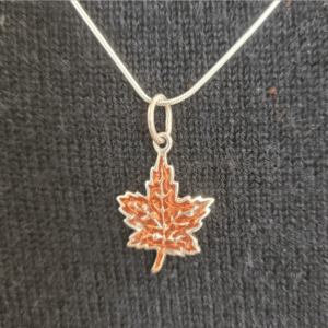 Closeup of maple leaf pendant on sterling silver snake chain