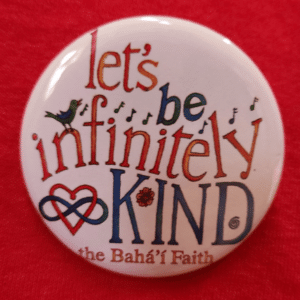 Bahai Infinitely Kind button on red shirt